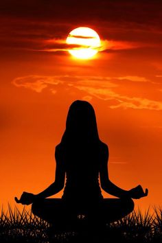 the silhouette of a woman meditating in front of a setting sun with words loving / kindness meditation