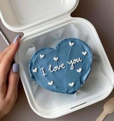 a heart shaped cake with the words i love you on it being held by a woman's hand