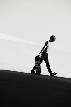 a man carrying a skateboard down a hill