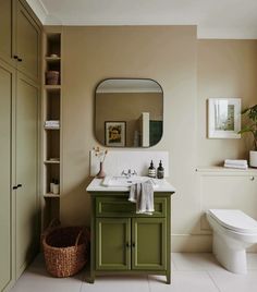 a bathroom with a toilet, sink and green cabinetry in it's center