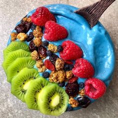 a blue bowl filled with fruit and granola on top of a gray countertop