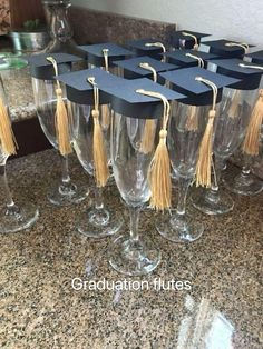 several wine glasses with graduation caps and tassels are lined up on the counter