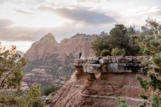 a bride and groom standing on the edge of a cliff at sunset in sedona