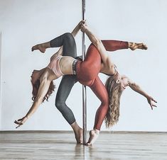 two people are doing acrobatic tricks on a pole