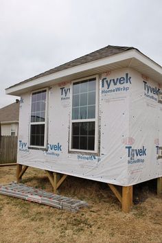 a house under construction with the roof covered in tarp and windows being installed on it