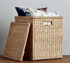 two wicker baskets sitting on top of a wooden table next to pillows and blankets