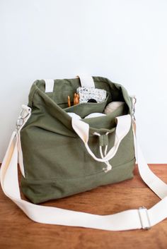 a green bag sitting on top of a wooden table next to a white wall and floor