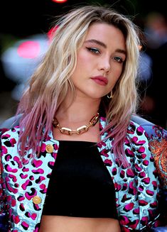 a woman with blonde hair wearing a black top and leopard print jacket is looking at the camera