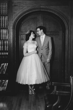 a man and woman standing next to each other in front of a book shelf filled with books