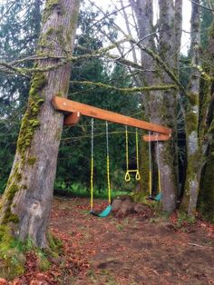 a wooden swing set in the woods with swings hanging from it's sides and trees