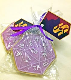 two cookies with purple frosting and numbers on them in plastic wrappers next to each other