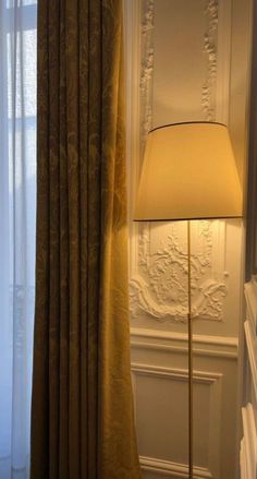 a lamp is next to a window in a room with white walls and drapes