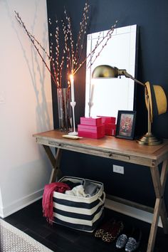 a desk with a mirror, vases and other items on it in front of a black wall