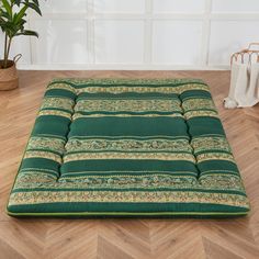 a green and gold striped futon mattress on the floor in front of a potted plant