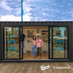 two people standing in the doorway of a shipping container that is made out of shipping containers