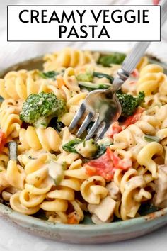 a bowl full of creamy veggie pasta with a fork in it