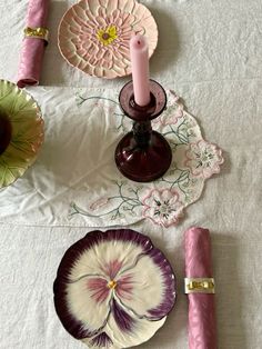 a table topped with plates and candles on top of a white tablecloth covered table