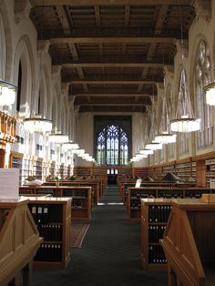 the interior of a large library with many bookshelves and lamps on either side