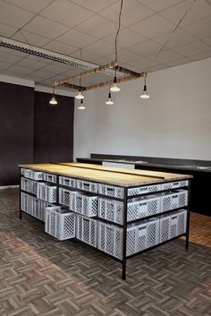 an empty room with several bins on the floor and lights hanging from the ceiling