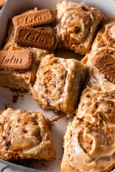 a pan filled with cinnamon rolls covered in frosting and graham crackers on top