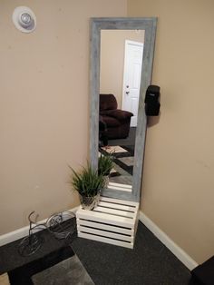 a mirror sitting in the corner of a room next to a chair and planter