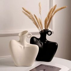 two black and white vases sitting on top of a table