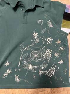 a green shirt with white drawings on it sitting on the floor next to other items