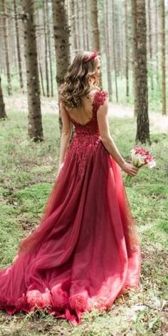 a woman in a red dress is walking through the woods with flowers on her head