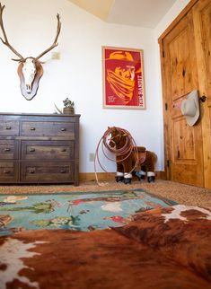 a room with a bed, dresser and antlers on the wall