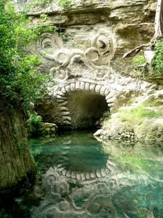 the water is clear and blue in this cave with carvings on it's walls