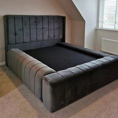 a black bed frame in a bedroom with carpeted flooring and white wall paint