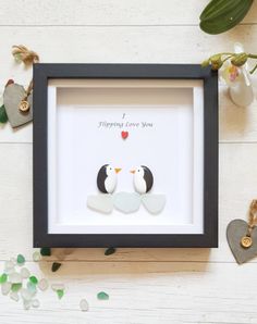 two penguins are sitting in a shadow box with the words i love you on it