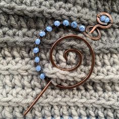 a close up of a metal object on top of a knitted blanket with beads