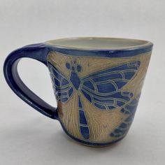 a blue and gold dragonfly mug on a white background