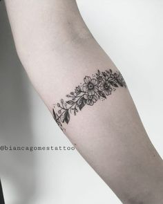 a black and white photo of a flower tattoo on the left upper half of the arm