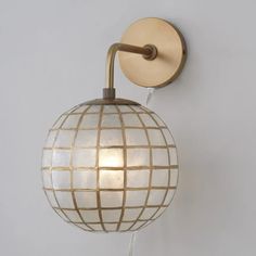 a wall light with a white ball on it's side and a wooden arm