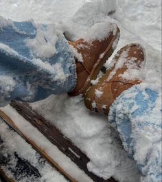 someone is standing in the snow with their feet on a sled and wearing brown boots