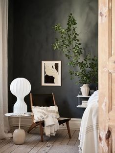 a chair and table in a room with dark green paint on the walls, white furniture and potted plant