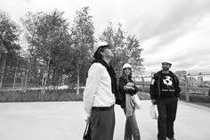 black and white photograph of three people standing on the street with trees in the background