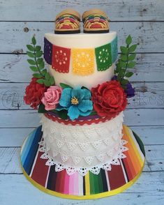 a multi - tiered cake decorated with colorful flowers and shoes on the top layer