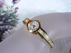 BUCHERER Sage Green Enamel and Cream & Pink Floral Bangle Wrist Watch - 17 Jewels - Mechanical Watch - Analog Watch - Vintage Wristwatch This is a beautiful 1960s BUCHERER Swiss Wrist Watch that is designed with Sage Green Enamel and Cream and Pink Flowers with Green Vines and Leaves.  It is just so very feminine and stunning!!  This watch is plated with 20 Microns of Yellow Gold Plating.  This watch is a wind-up Mechanical Watch that is keeping excellent time and it runs very well... a quiet ti Green Watch Aesthetic, Luxury Green Watch Bracelet Strap, Vintage Gold Watch, Thought Daughter, Green Vines, Black Numbers, Flower Watch, Green Watch, Gold Watches Women