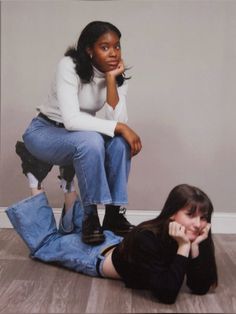 two young women sitting on the floor posing for a photo