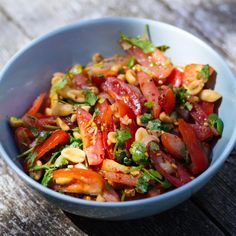 a blue bowl filled with salad on top of a wooden table