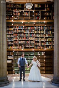 a bride and groom standing in front of a library full of books