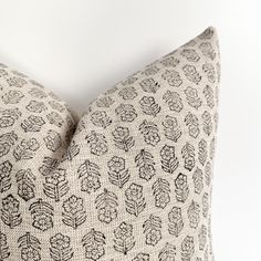 a close up of a decorative pillow on a white background with black and grey leaves