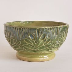 a green ceramic bowl sitting on top of a white table