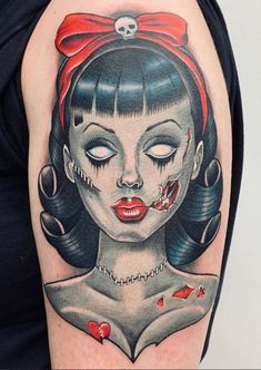 a woman's arm with a skull and red bow on it, her eyes are closed