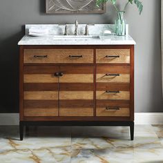 a bathroom vanity with marble counter top and wooden cabinetry, along with a painting on the wall