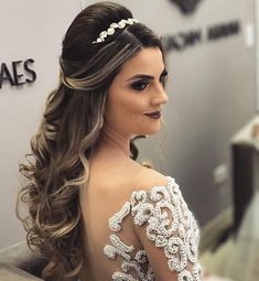 a woman with long hair wearing a white dress and pearls in her hair is looking off to the side