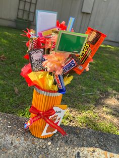 an orange vase filled with candy and candies on top of a cement slab in front of a building